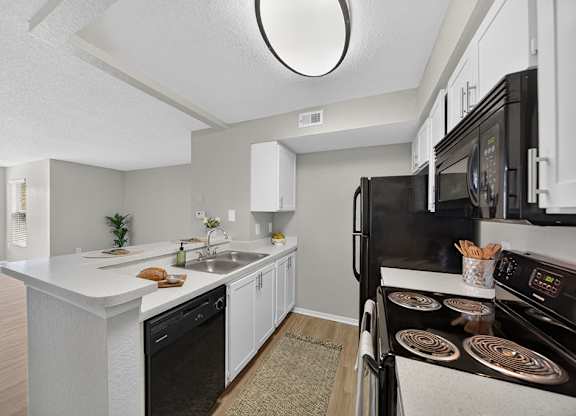 A modern kitchen with black appliances and white cabinetry.