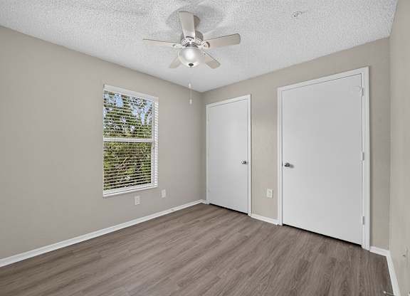 A room with a ceiling fan and a window with blinds.