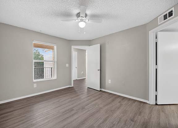 A room with a ceiling fan and a window with blinds.