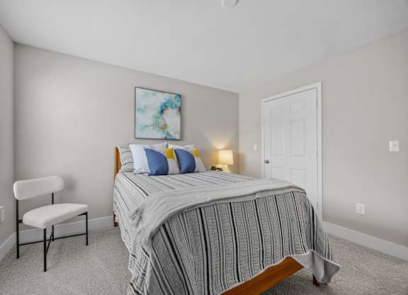A bedroom with a bed, chair, and painting.
