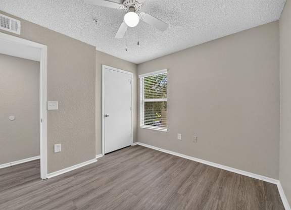 A room with a ceiling fan and a window with blinds.