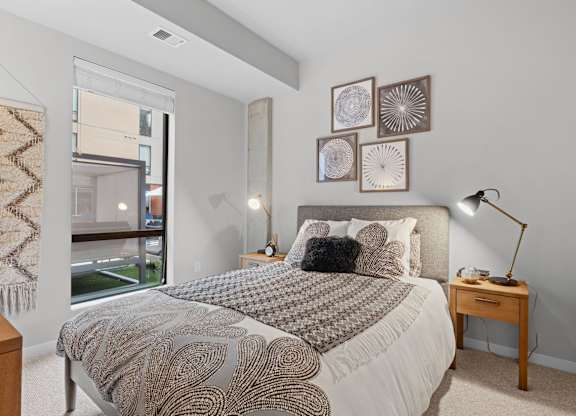 A bedroom with a large bed and a window overlooking a balcony.