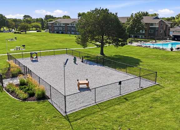 A playground with a trampoline surrounded by a fence.