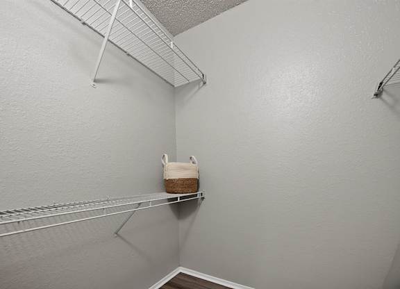 A small closet with a shelf and a basket on it.
