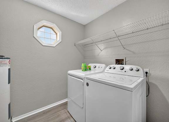 A white washing machine in a laundry room with a window above it.