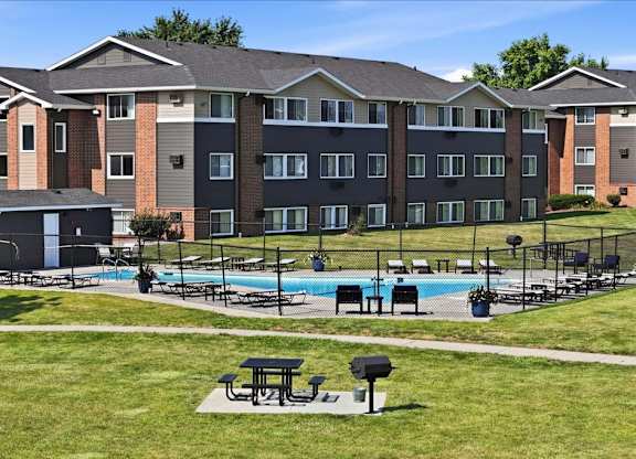 A large apartment complex with a pool and picnic tables.