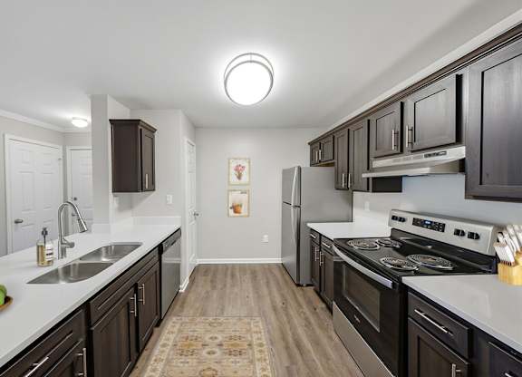 A kitchen with dark wood cabinets and a white countertop.
