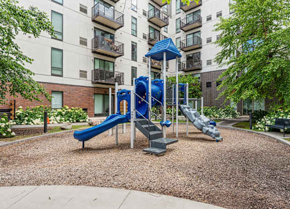 A playground with a blue slide and a white railing.