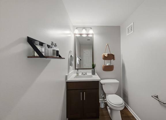 A bathroom with a toilet, sink, and mirror.