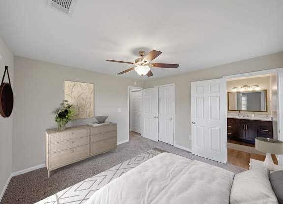 A bedroom with a white bed and a ceiling fan.