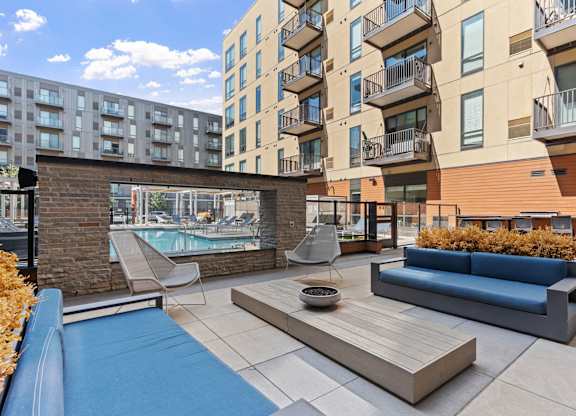 A modern outdoor seating area with a pool and a brick wall.