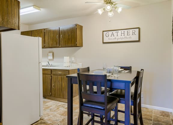 a dining area with a table and chairs and a kitchen with a refrigerator