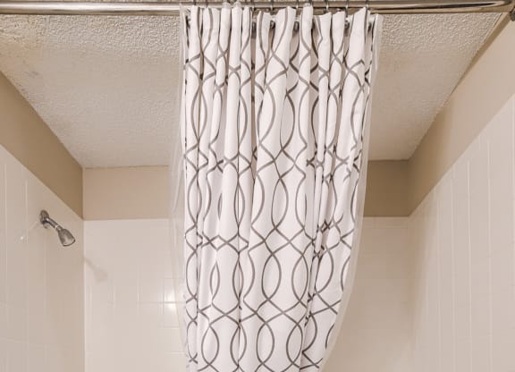 a white bathroom with a shower curtain and a tub