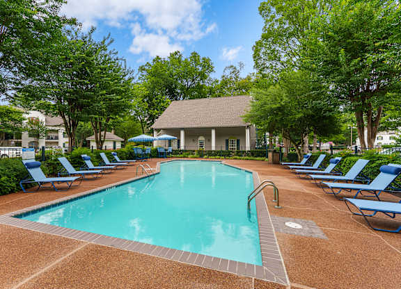 A large swimming pool surrounded by blue lounge chairs.