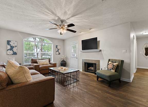 A living room with a brown couch, a fireplace, and a television.