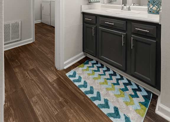 A bathroom with a sink, mirror, and cabinets.