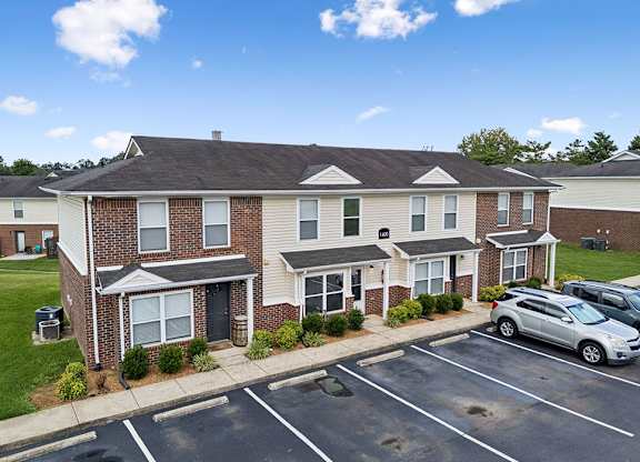 A residential building with a parking lot in front.