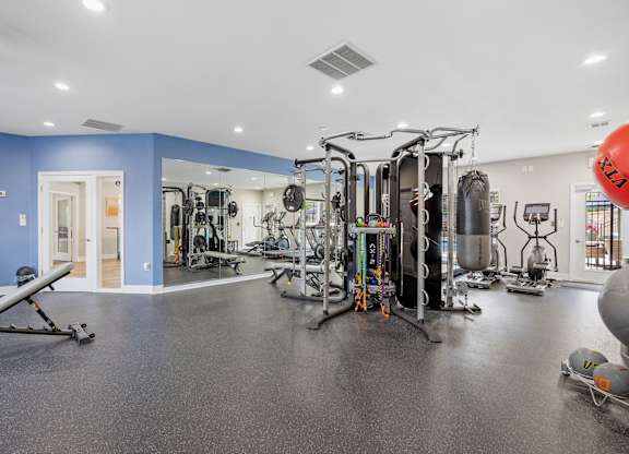 A gym with a variety of equipment including a leg press machine, a squat rack, and a bench press.