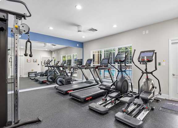 A gym with treadmills, elliptical machines, and other exercise equipment.