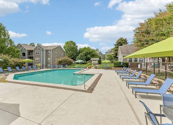 A large swimming pool surrounded by lounge chairs and umbrellas.