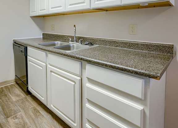 A kitchen with white cabinets and a granite countertop.