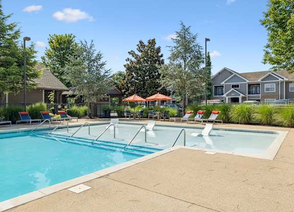 A large swimming pool with a few chairs and umbrellas.