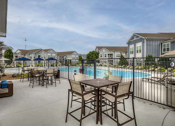 A poolside table and chairs are set up on a patio.
