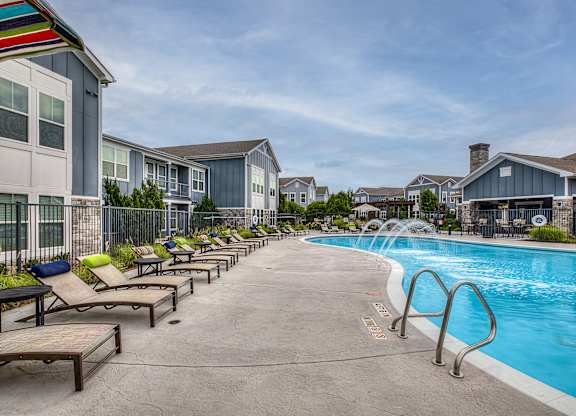 A pool area with sun loungers and a fence.