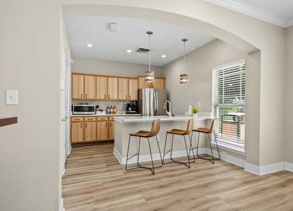 A kitchen with wooden floors and a bar area with two chairs.