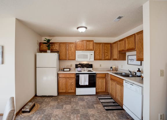 Spacious Kitchen With Tile-Style Flooring, Oak Cabinets & White Appliances
