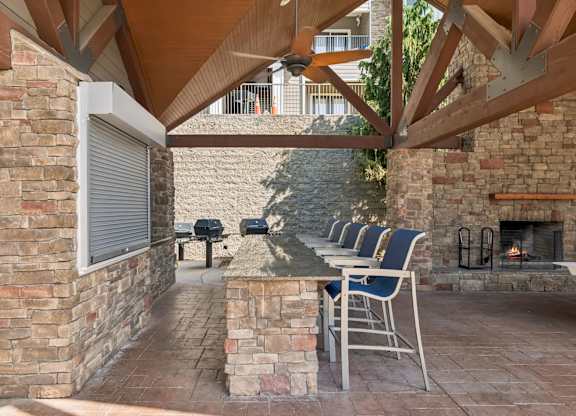 A patio with a fireplace and chairs.