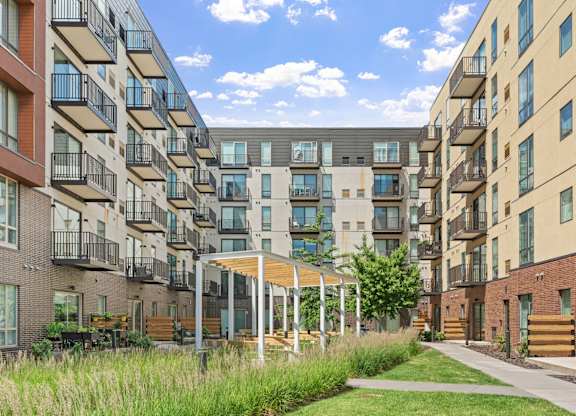A row of apartment buildings with balconies and a grassy area in front.