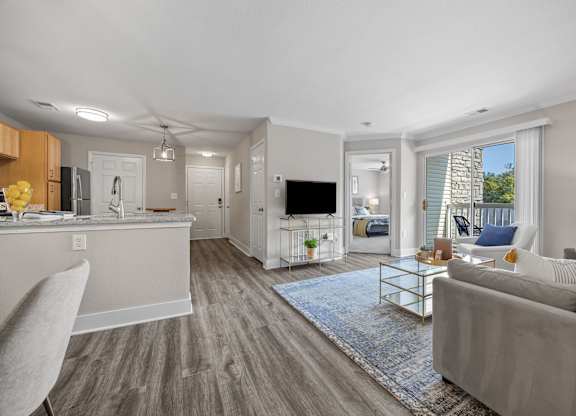 A modern living room with a grey couch and a kitchen area in the background.