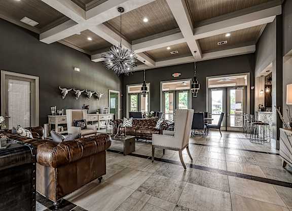 A living room with a brown leather couch and a wooden floor.