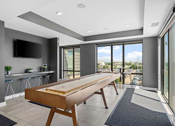 A modern kitchen with a long wooden table and a flat screen TV mounted on the wall.