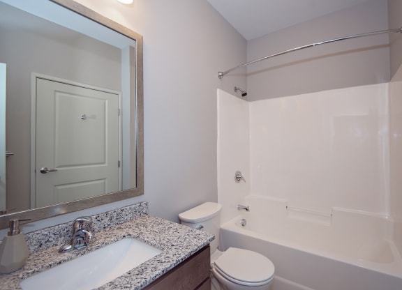 Spacious Bathroom with Granite Countertop Vanity and Shower with Tub