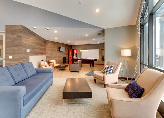 a living room with a blue couch and chairs and a pool table