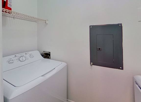 A white washing machine sits in a laundry room.