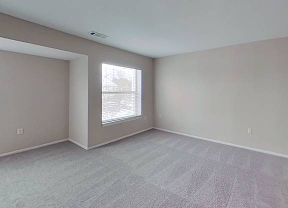 A room with a large window and a carpeted floor.
