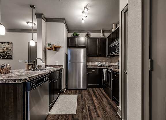 A kitchen with a stainless steel refrigerator and wooden floors.