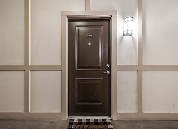A brown door with a welcome mat in front of it.