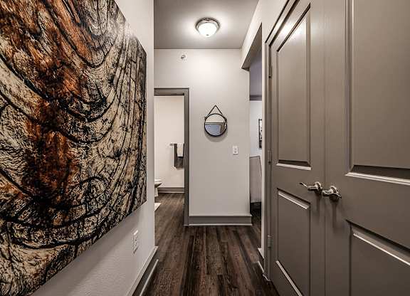 A hallway with a large painting on the wall and a wooden floor.