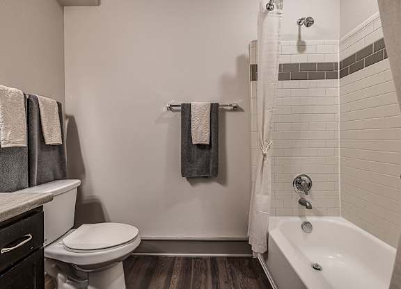 A white toilet sits next to a white bathtub in a bathroom.