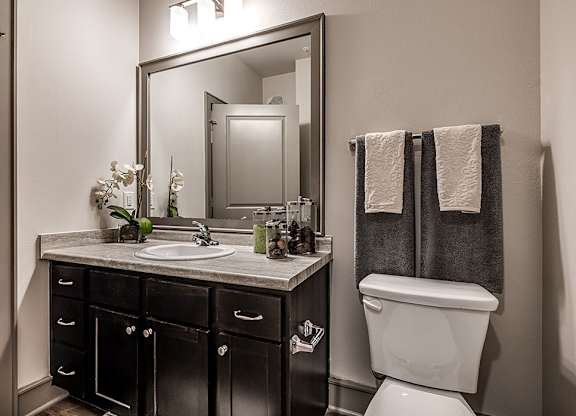 A bathroom with a sink, mirror, toilet and towel rack.