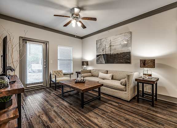 A living room with a couch, a chair, a coffee table, and a painting on the wall.