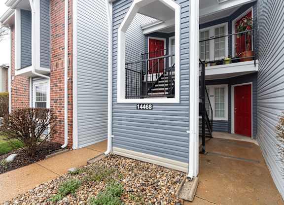 A grey, multi-level home with red doors and a balcony.