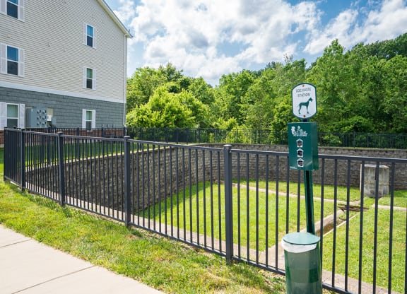 a black wrought iron fence surrounding a yard with a green sign on it
