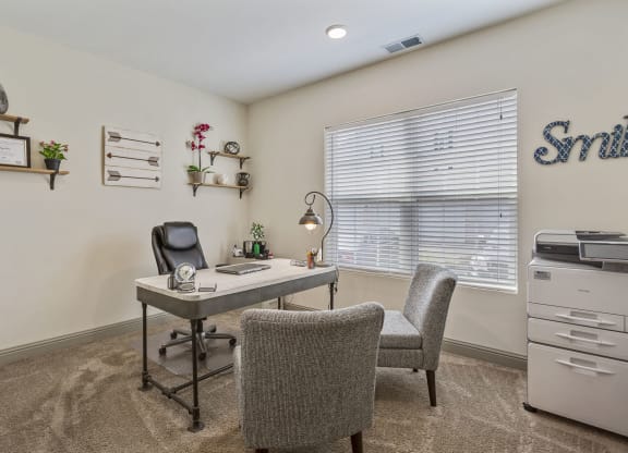 an office with a desk and chairs and a window