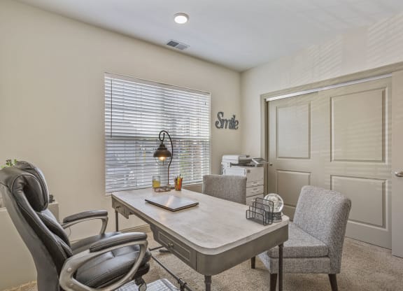 a home office with a desk and chairs and a window