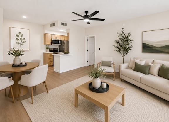 A living room with a couch, coffee table, and a dining table.